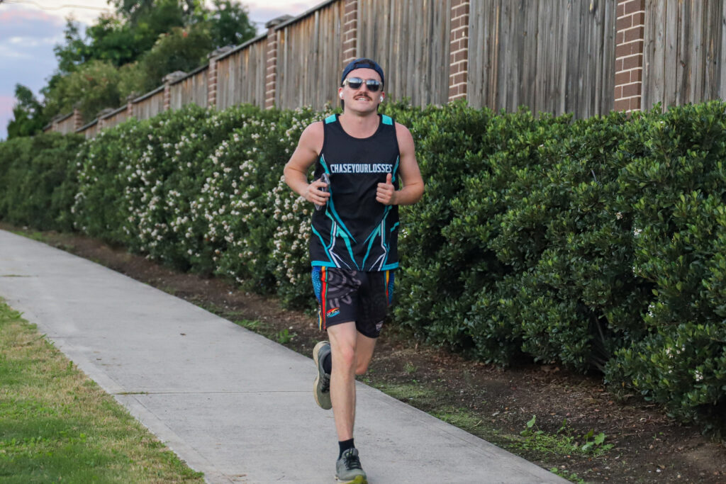 A runner completing an easy solo lap along a path at dusk