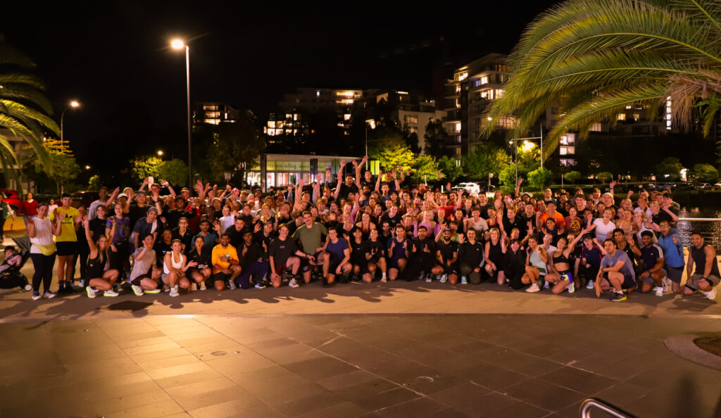 A large group of Hills Run Club members posing together outdoors at a night run