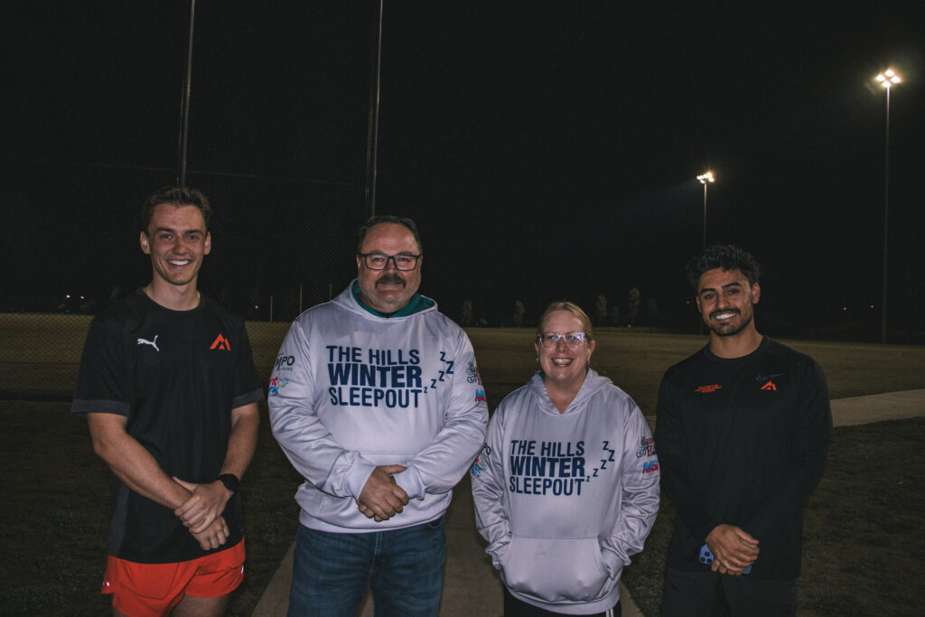 Two smiling Hills Run Club members in running tops standing side by side at night