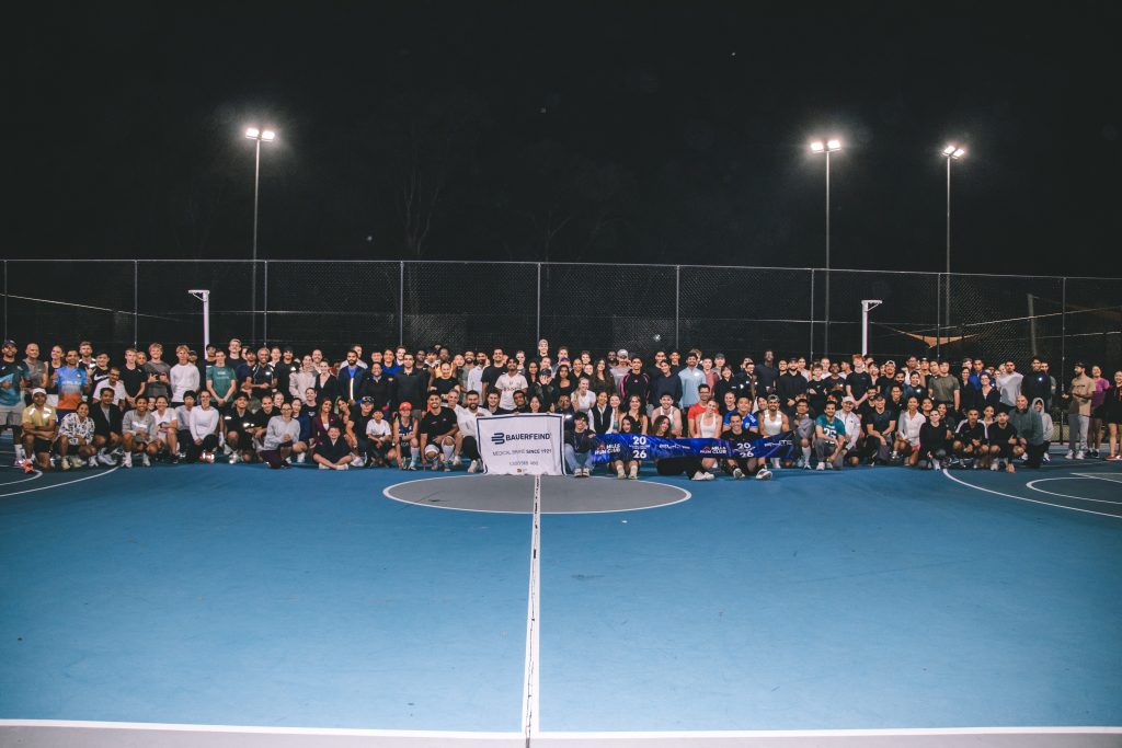 A large group of runners gathered together on a lit court at night