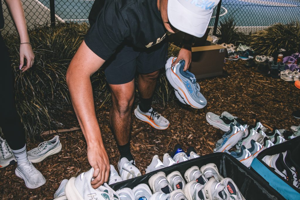 A runner sorting through a pile of running shoes at a Hills Run Club night run