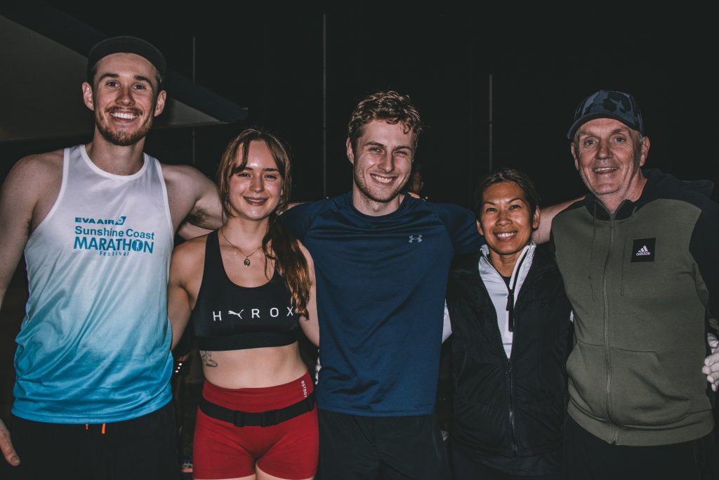 Five smiling Hills Run Club members with their arms around each other at a night run