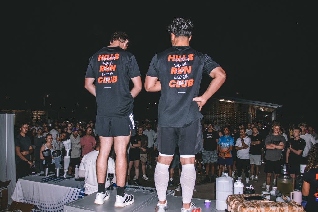 Runners gathered together at night at a Hills Run Club community run