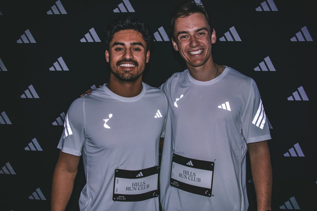 Harrison Ross and Nicholas Cutroni with their Hills Run Club placards in front of the adidas wall